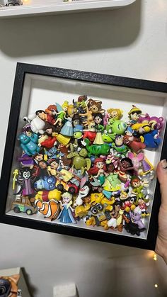 a person holding up a framed photo with many cartoon characters on it's side