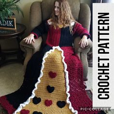 a woman sitting in a chair wearing a crocheted blanket