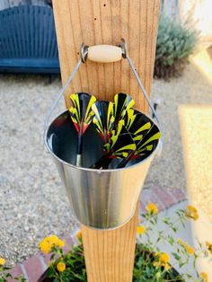 a metal bucket filled with flowers next to a wooden pole