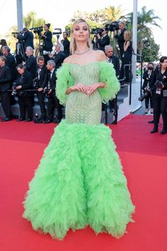 a woman in a green gown standing on a red carpet