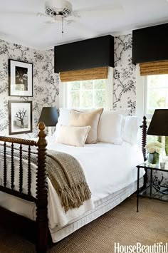 a white bed sitting in a bedroom next to a window with black and white wallpaper