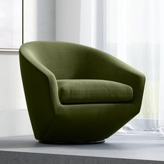 a green chair sitting on top of a white table next to a window with curtains