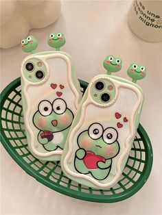 two cell phones with faces painted on them sitting on a green tray next to each other