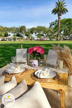 the table is set with plates and napkins for two people to eat outside in the grass