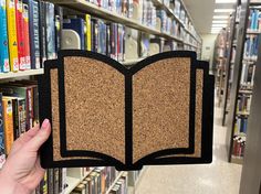 a person holding up a book in front of a library full of bookshelves