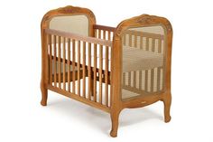 a wooden crib with wicker and wood trimmings on the sides, against a white background