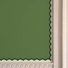 a green wall with white trim and scalloped edges