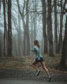 a woman running in the woods on a foggy day