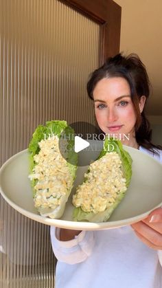 a woman holding a plate with two lettuce halves on it