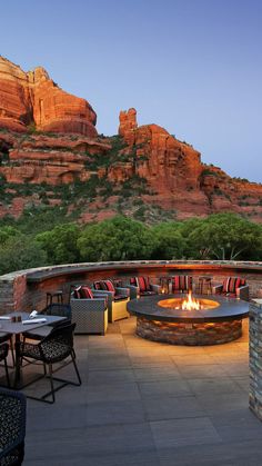 an outdoor fire pit surrounded by chairs and tables