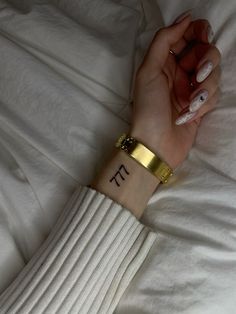 a woman's wrist with the word pi tattooed on her left hand, while she is laying in bed