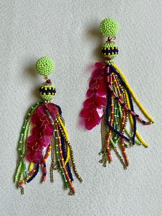 two pairs of colorful beaded earrings on a white surface with beads hanging from them