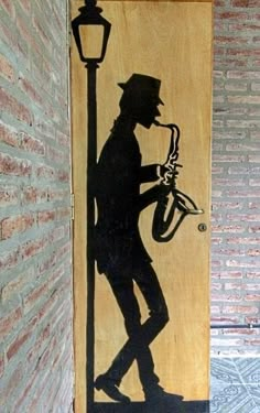 a wooden door with a silhouette of a man playing the saxophone and holding a lamp post