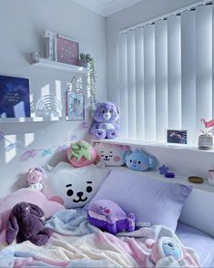 there are many stuffed animals on the bed in this small child's room with white walls