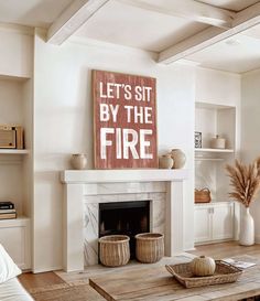 a living room filled with furniture and a fire place in front of a painting that reads let's sit by the fire