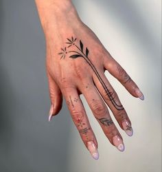 a woman's hand with tattoos on it and a flower tattooed on the ring finger