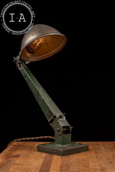 an old fashioned desk lamp sitting on top of a wooden table