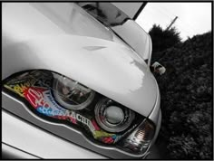 the front end of a white car with graffiti painted on it's grilles