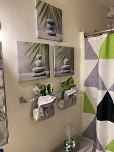 a bathroom decorated in green and white with pictures on the wall above the shower curtain