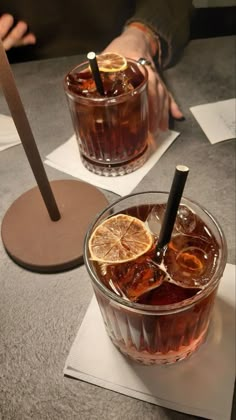 two glasses filled with drinks sitting on top of a table