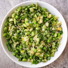 a white bowl filled with green vegetables on top of a table