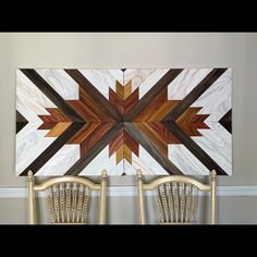 two chairs sitting next to each other in front of a large wooden wall art piece