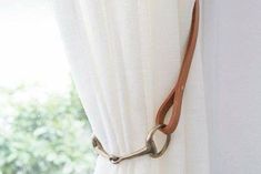 a curtain with a metal hook hanging from it's side next to a window