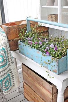 an old wooden box filled with flowers on top of a white table next to a potted planter