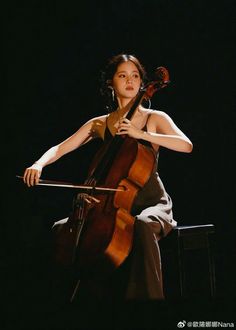 a woman is playing the cello on stage