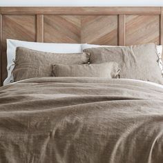 an unmade bed with two pillows and some blankets on top of the headboard