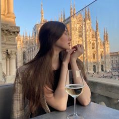 a beautiful woman sitting at a table with a glass of wine in front of her