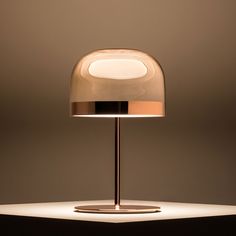 a table lamp that is on top of a white surface with light coming from it