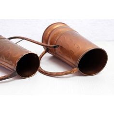 two old metal cups sitting next to each other on top of a white tablecloth