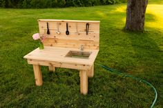 a wooden bench sitting in the grass with a sink on it's back end