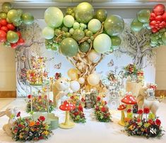 a table topped with lots of balloons and stuffed animals next to a tree filled with flowers