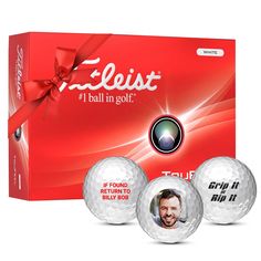 three golf balls in front of a red box with an image of a man's face on it