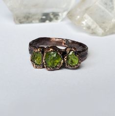 This is a raw peridot three stone ring. The ring has a hammered copper band, then is plated in a thick layer of copper and given an antique finish. This ring is made to order the pictures are an example of what you will recieve. Your finished ring will be in the same style as the one pictured. There may be slight variations in stone shape and size. Every ring will be unique. The peridot stones used are from an Apache reservation in Arizona. They have not been dyed, cut, or polished. Each ring is hand shaped, polished, and sealed to prevent tarnishing. Message me if you have any questions (: Raw Peridot, Electroformed Ring, Aqua Aura Quartz, Raw Stone Necklace, Raw Stone Ring, Copper Style, Phantom Quartz, Peridot Stone, Three Stone Ring