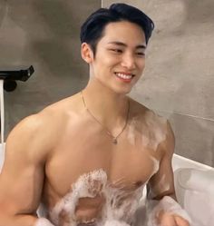 a man is sitting in the bathtub with soap on his body and smiling at the camera