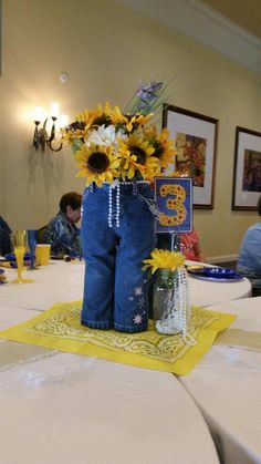 a vase filled with sunflowers sitting on top of a white tablecloth covered table