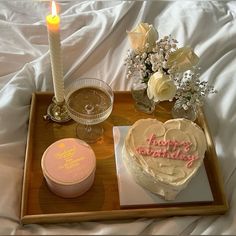 a heart shaped cake on a tray next to a candle and some other items for a birthday