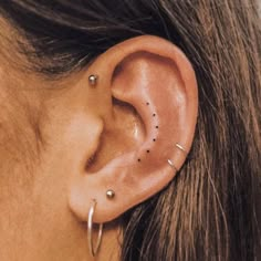 a woman's ear with small black dots on the middle part of her left ear