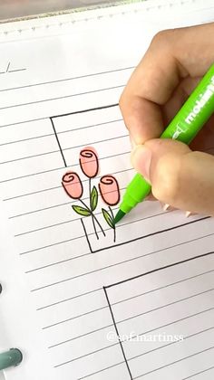 someone is drawing flowers on lined paper with green marker pens and pencils in front of them