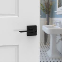 a bathroom door with a black handle on it and a white sink in the background