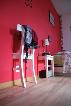 a bedroom with red walls and white furniture on the floor, along with a bed