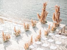 an outdoor wedding setup with chairs and flowers on the side of the water's edge