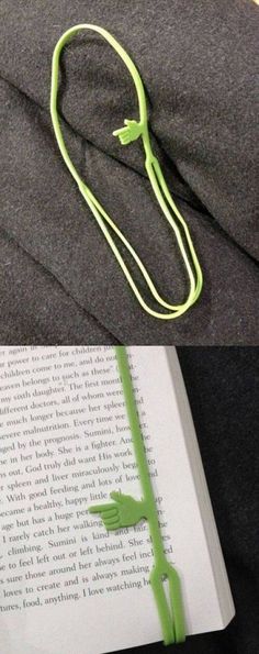 an open book laying on top of a bed next to a neon green string attached to it