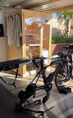 a bicycle parked next to a bike rack in front of a building with open doors