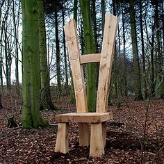 a wooden chair sitting in the middle of a forest