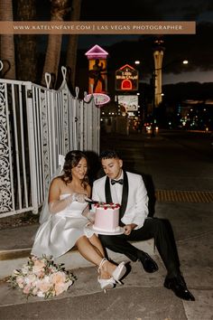 a man and woman sitting on the ground with a cake