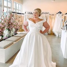 a woman in a white dress standing next to some dresses